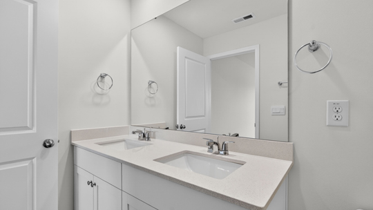 primary bathroom with walk in shower and dual vanity sinks