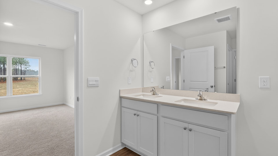 primary bathroom with walk in shower and dual vanity sinks