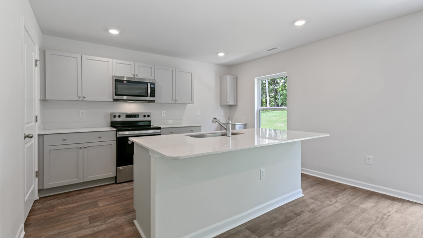 kitchen with quartz counters, kitchen island, pantry, stainless steel appliances