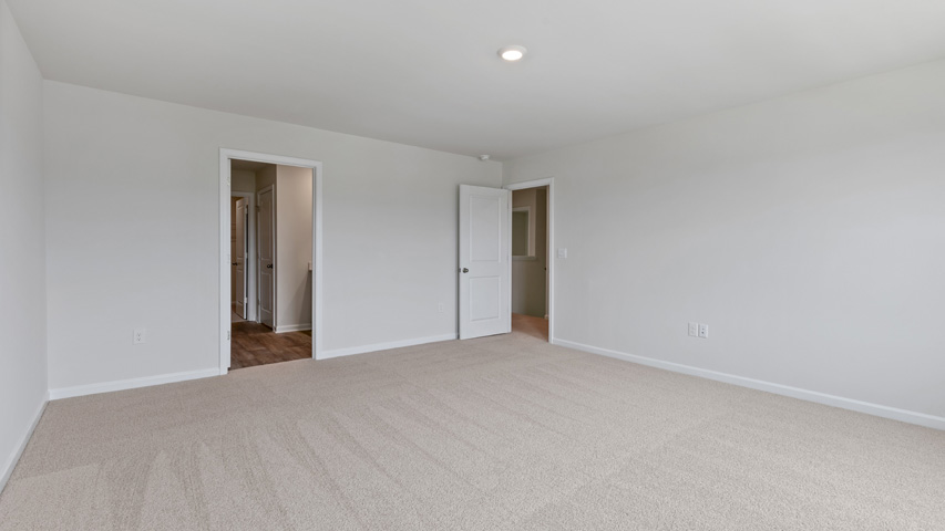 primary bedroom with two windows and carpeting, attached bath