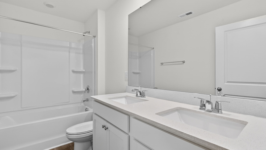 bathroom with dual vanity quartz countertops and tub shower combo
