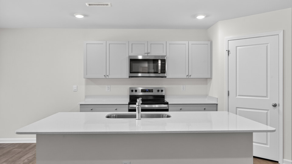kitchen with quartz counters, kitchen island, pantry, stainless steel appliances