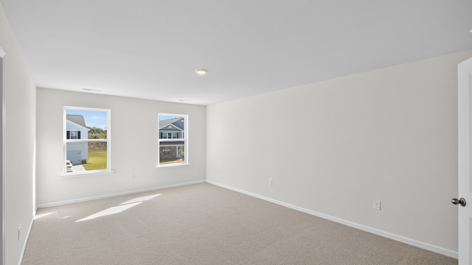 primary bedroom with two windows and carpeting, attached bath