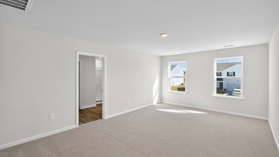 primary bedroom with two windows and carpeting, attached bath