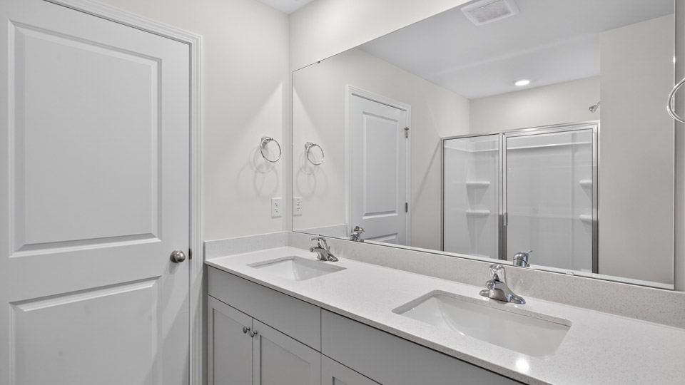 primary bathroom with walk in shower and dual vanity sinks