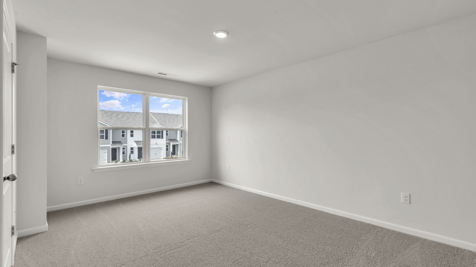 primary bedroom with two windows and carpeting, attached bath