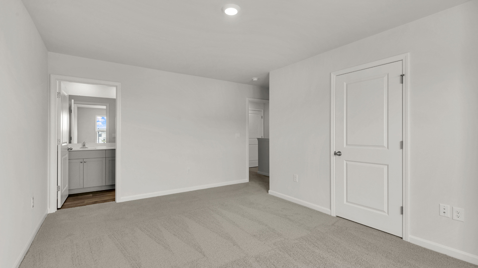 primary bedroom with two windows and carpeting, attached bath