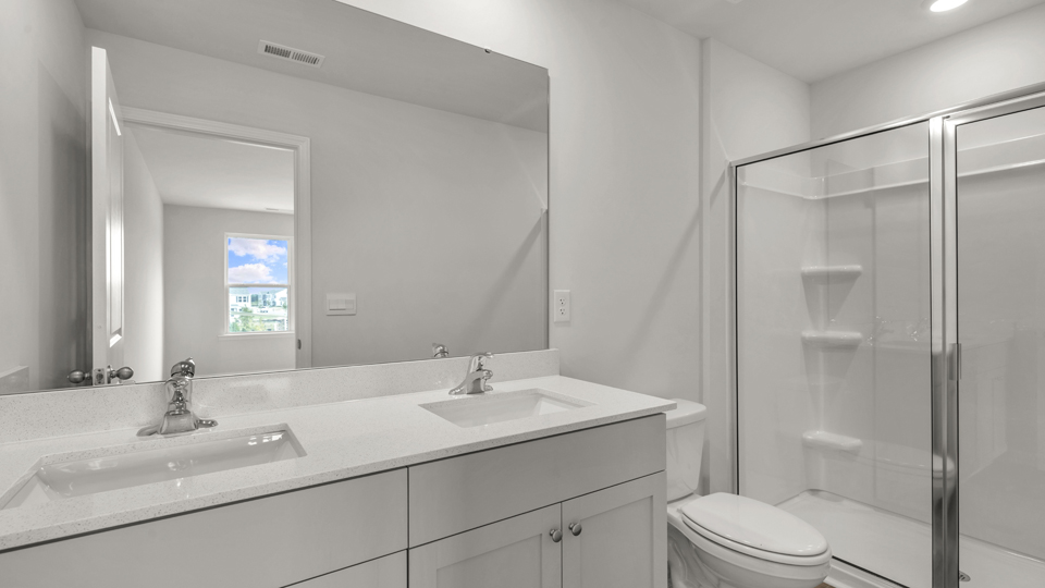 primary bathroom with walk in shower and dual vanity sinks