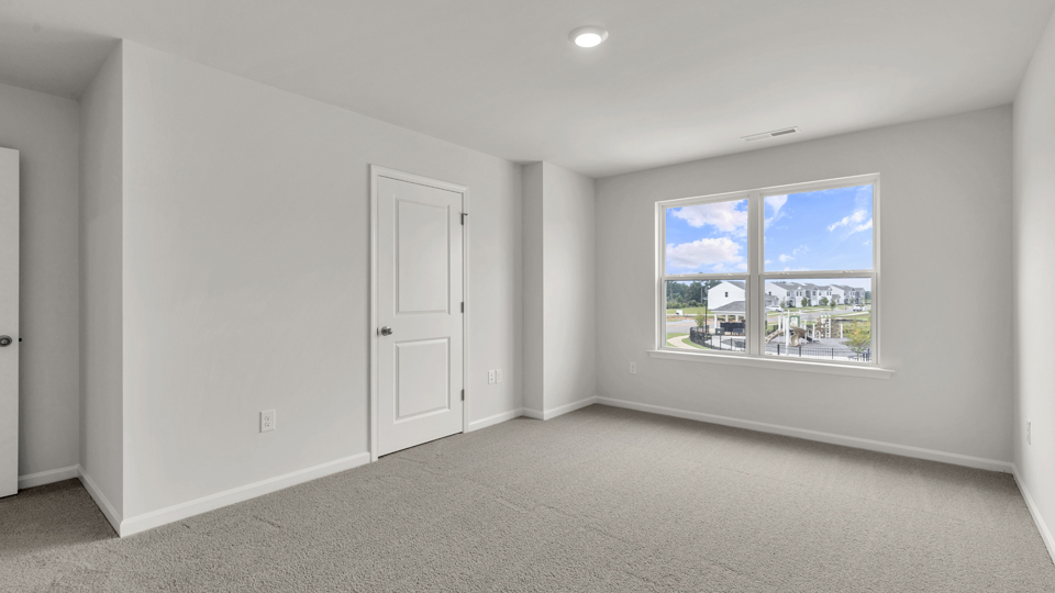 primary bedroom with two windows and carpeting, attached bath