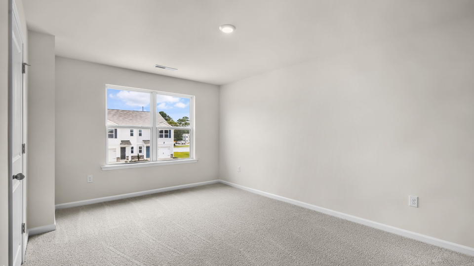 primary bedroom with two windows and carpeting, attached bath