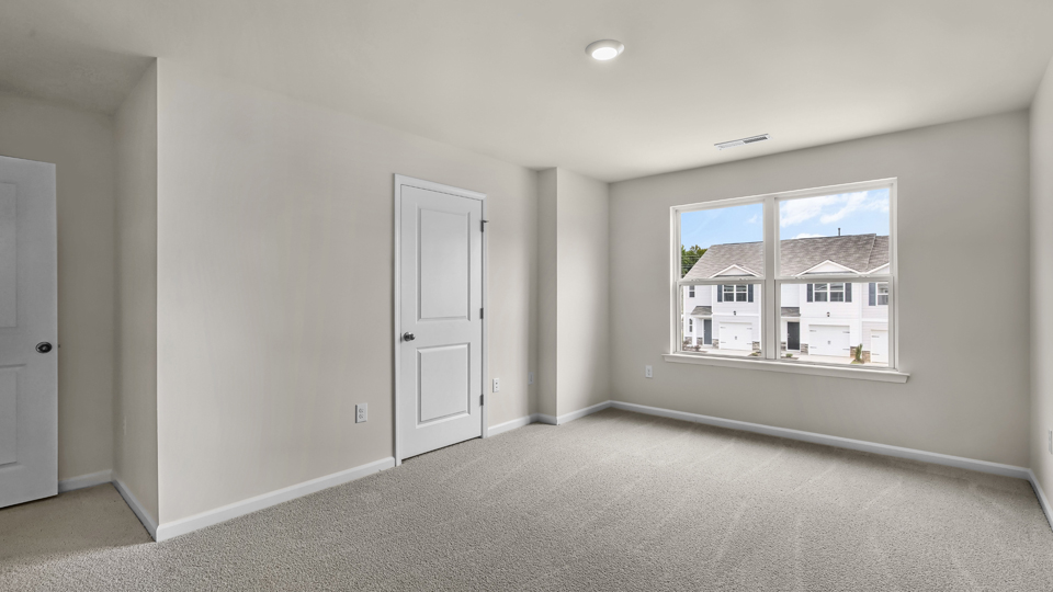 primary bedroom with two windows and carpeting, attached bath