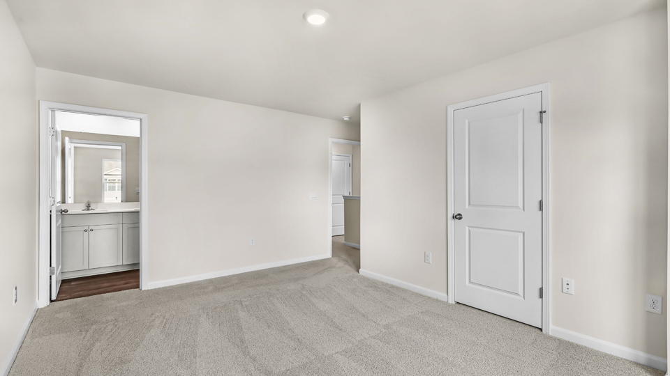 primary bedroom with two windows and carpeting, attached bath