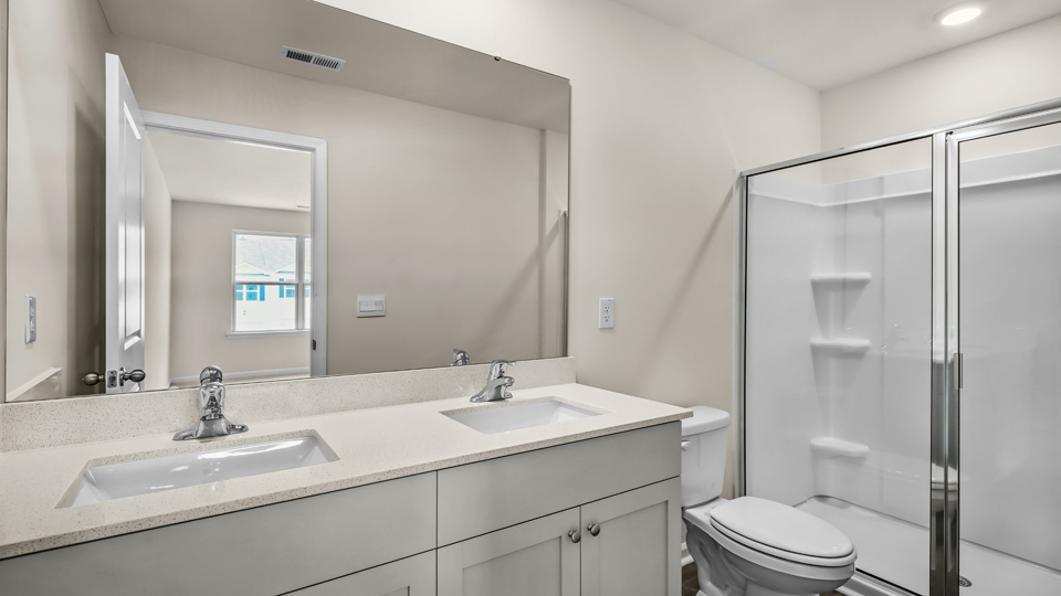 primary bathroom with walk in shower and dual vanity sinks