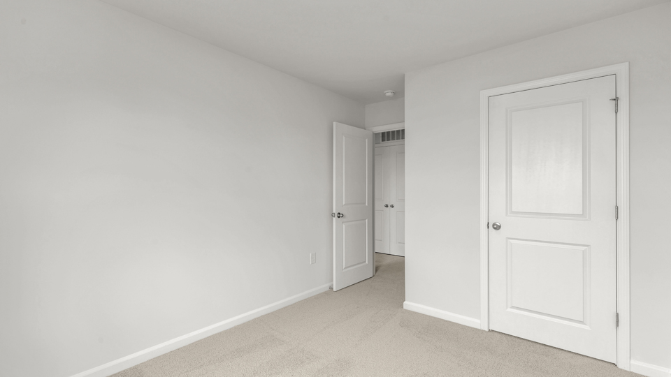 primary bedroom with two windows and carpeting, attached bath