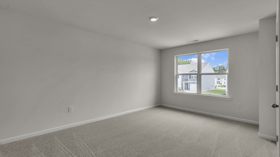 primary bedroom with two windows and carpeting, attached bath