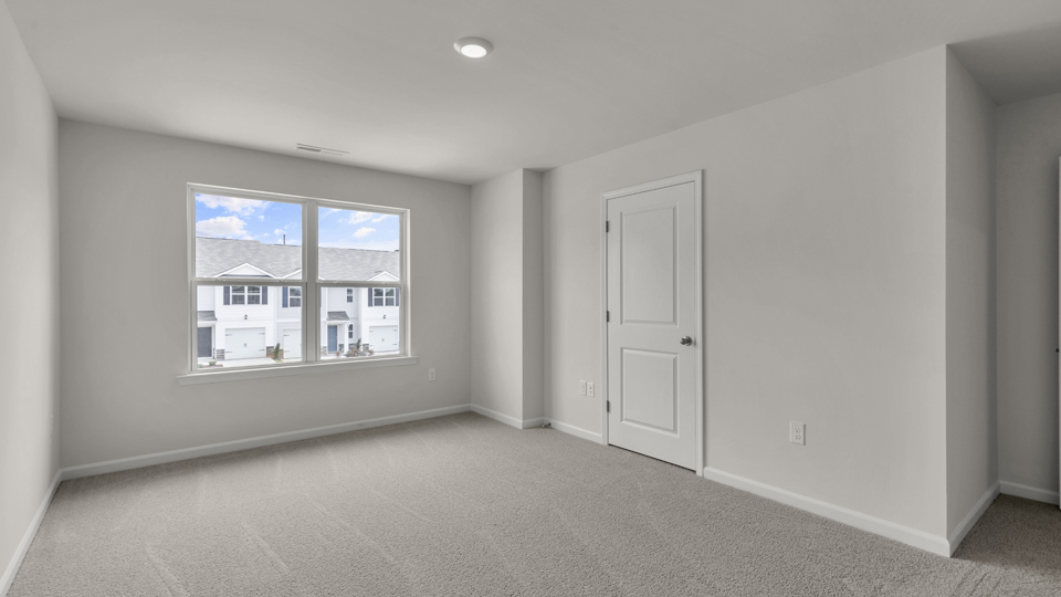 primary bedroom with two windows and carpeting, attached bath