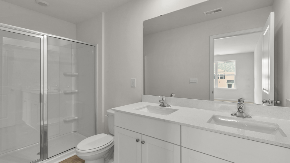 primary bathroom with walk in shower and dual vanity sinks