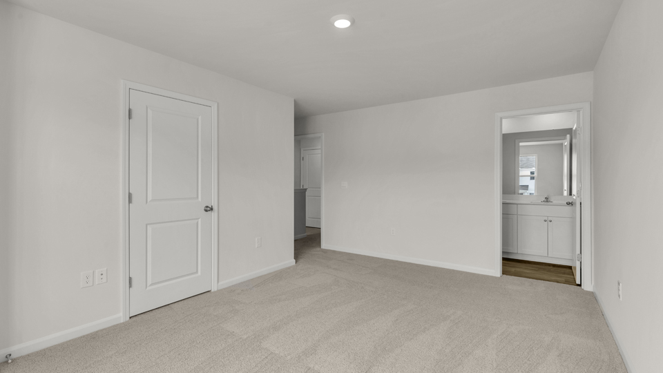 primary bedroom with two windows and carpeting, attached bath