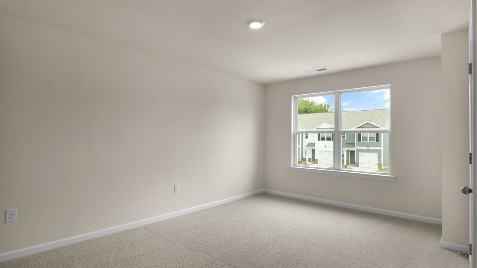 primary bedroom with two windows and carpeting, attached bath