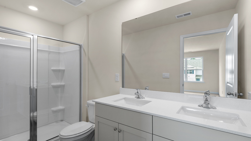 primary bathroom with walk in shower and dual vanity sinks