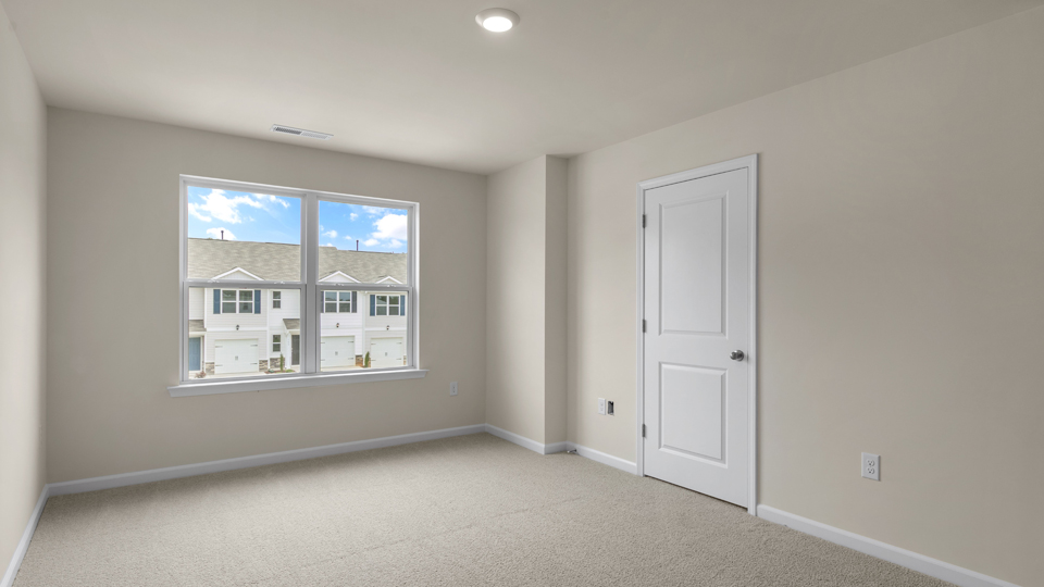 primary bedroom with two windows and carpeting, attached bath