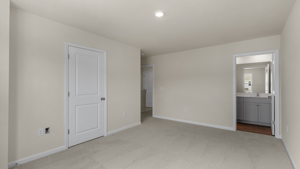 primary bedroom with two windows and carpeting, attached bath