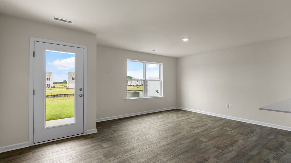 open floorplan living and dining room with lvp flooring, door to patio with concrete slab