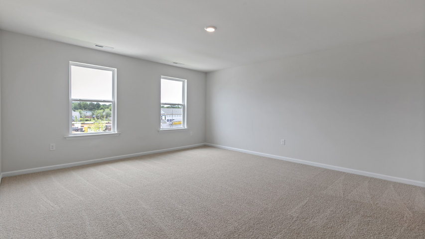 primary bedroom with two windows and carpeting