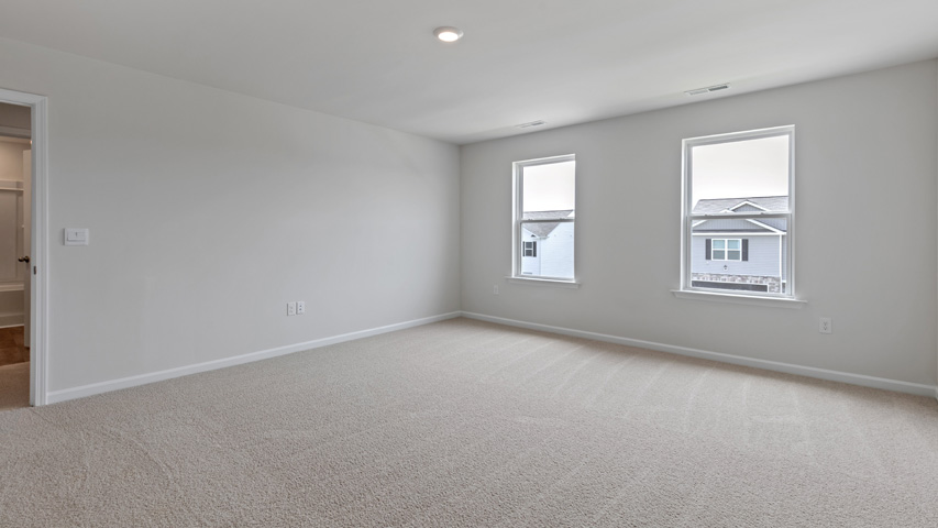 primary bedroom with two windows and carpeting