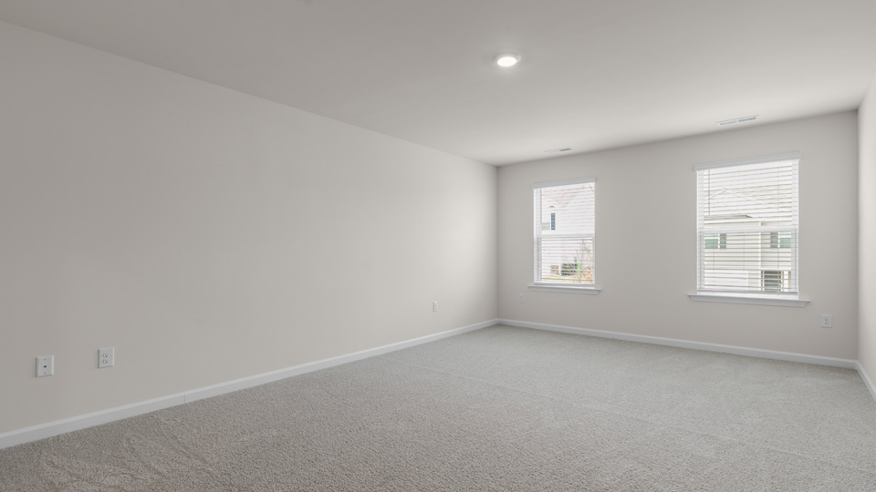 primary bedroom with two windows and carpeting