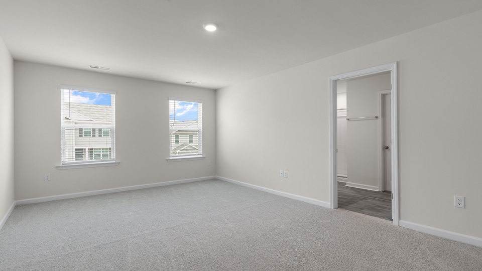 primary bedroom with two windows and carpeting, view of attached bathroom
