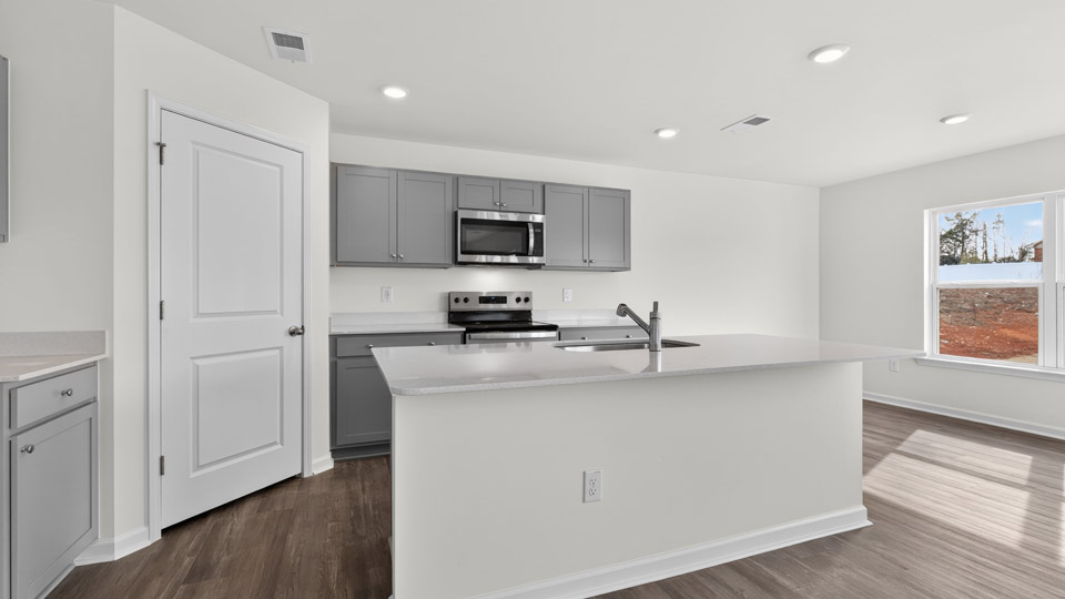 kitchen with quartz counters, kitchen island, pantry, stainless steel appliances