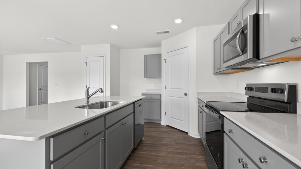 kitchen with quartz counters, kitchen island, pantry, stainless steel appliances