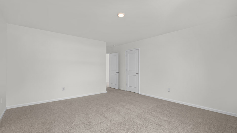 primary bedroom with two windows and carpeting, attached bath