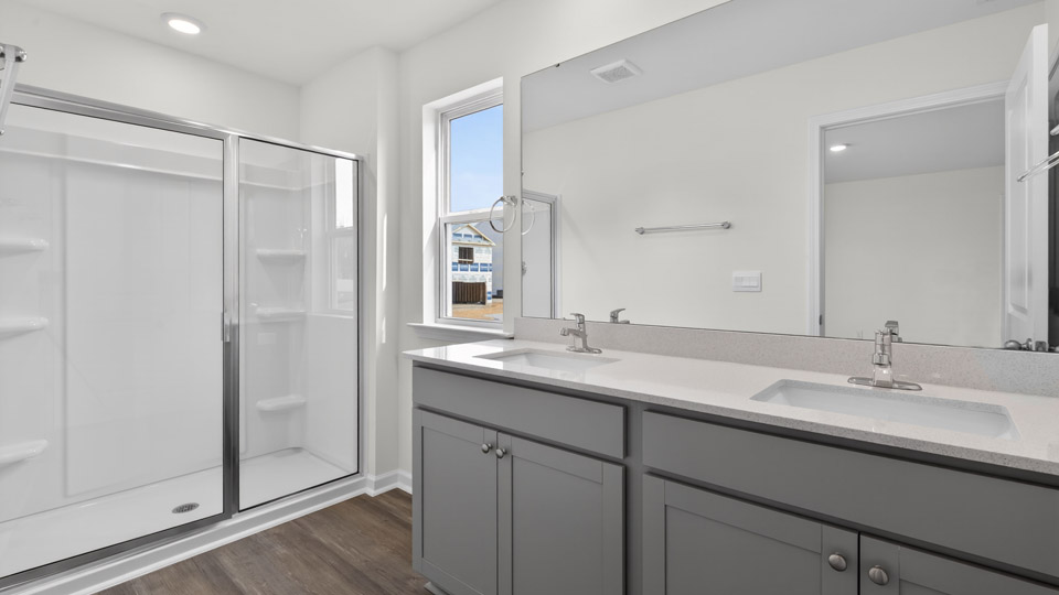 primary bathroom with walk in shower and dual vanity sinks