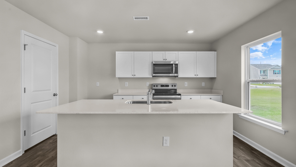 kitchen with quartz counters, kitchen island, pantry, stainless steel appliances