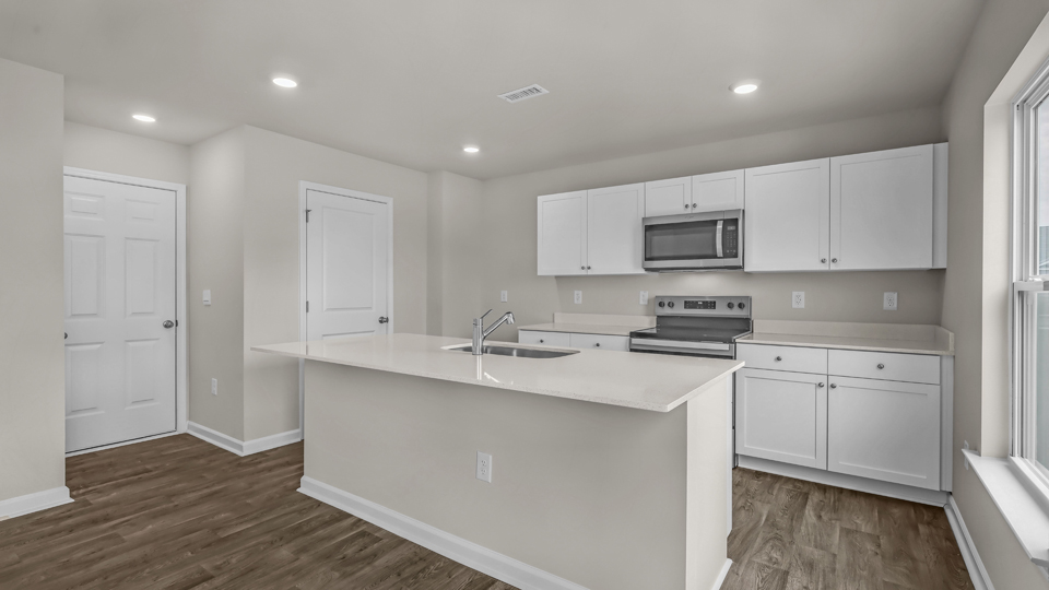 kitchen with quartz counters, kitchen island, pantry, stainless steel appliances