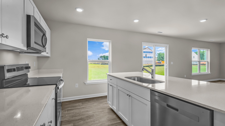 kitchen with quartz counters, kitchen island, pantry, stainless steel appliances