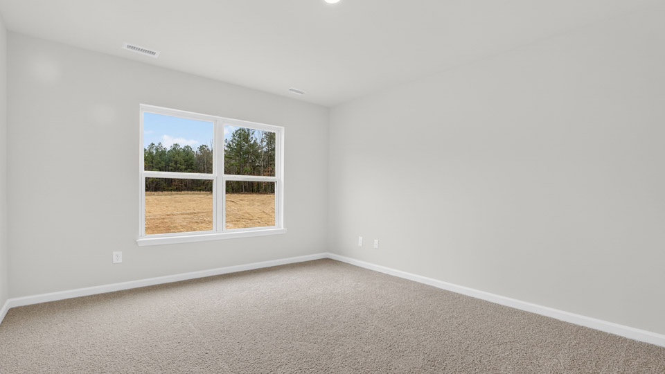 primary bedroom with two windows and carpeting, attached bath