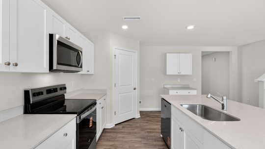 kitchen with quartz counters, kitchen island, pantry, stainless steel appliances