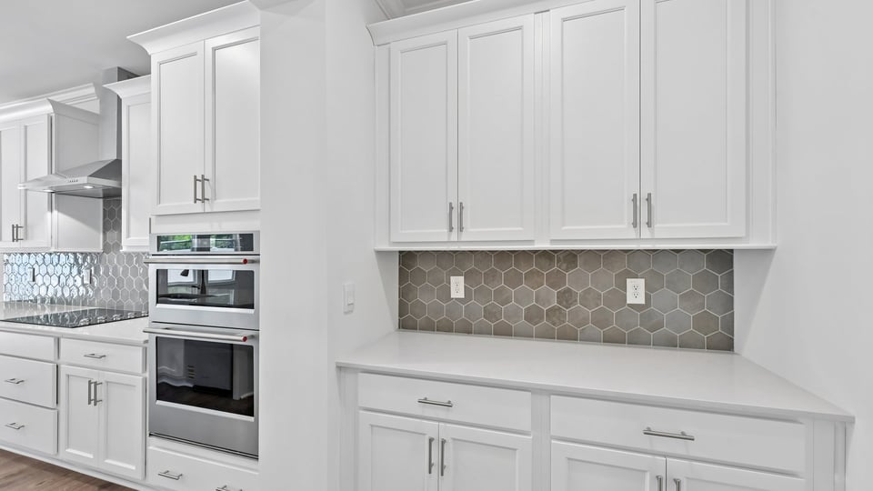butlers pantry area with white cabinets and quartz countertops