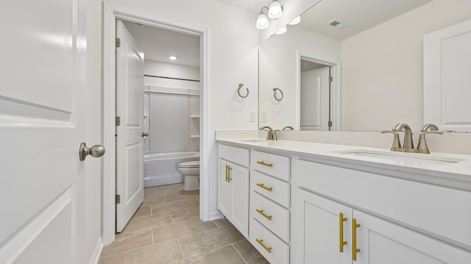 bathroom with dual vanity white cabinets and walkin closet