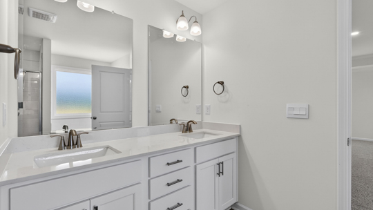 bathroom with dual vanity quartz countertops and white cabinets