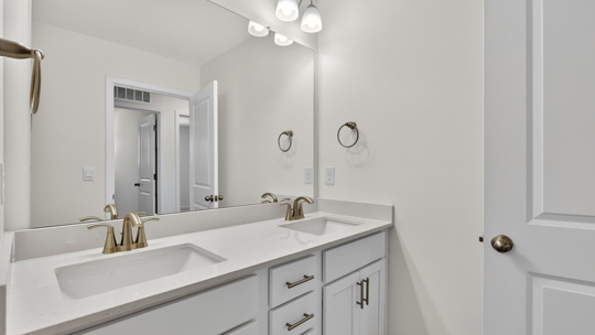 bathroom with dual vanity and quartz countertops