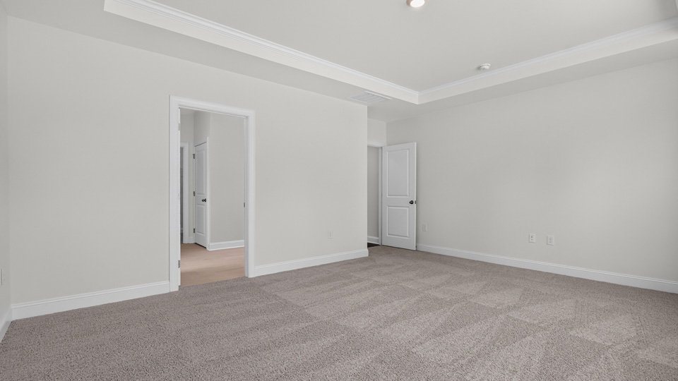 primary bedroom with two windows and carpeting, attached bath