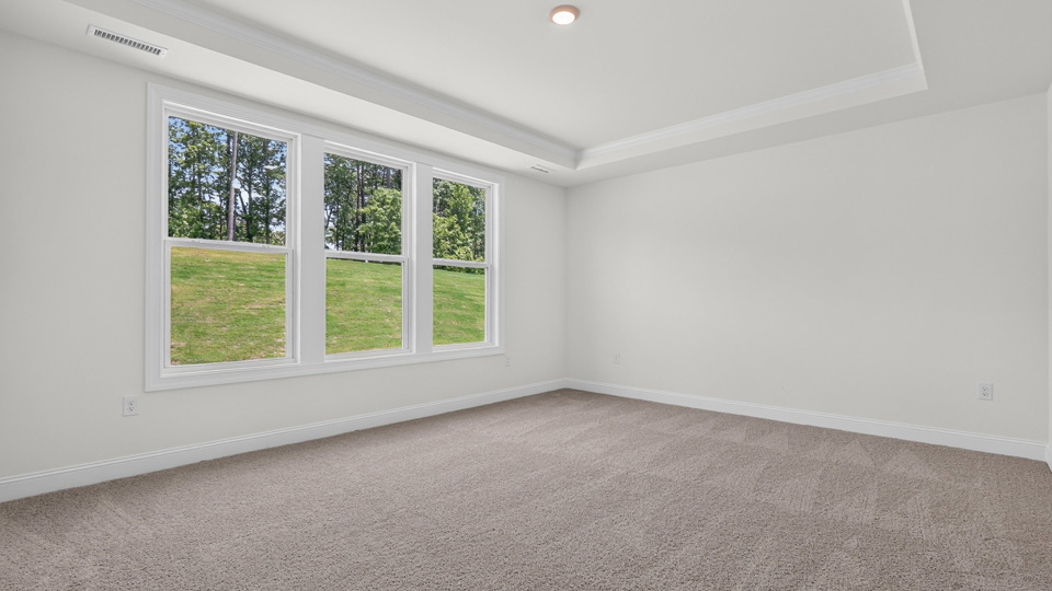 primary bedroom with two windows and carpeting, attached bath