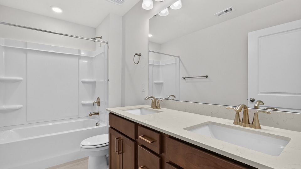 secondary bathroom with shower tub combo and dual vanity sink