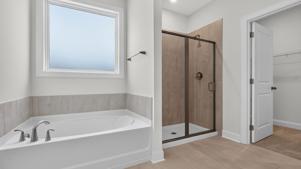 primary bathroom with walk in shower, bathtub, and dual vanity sinks