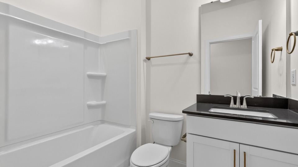 bathroom with tub shower combo and white cabinest