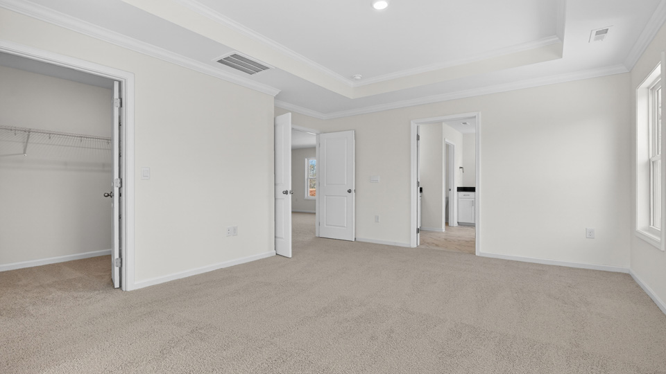 primary bedroom with carpet flooring and tray ceiling
